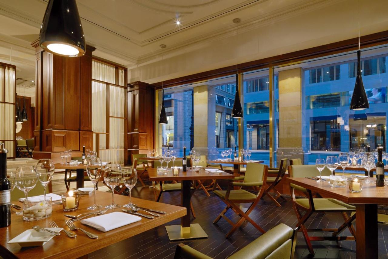 Hotel The Westin Grand Berlino Esterno foto The photo shows an elegant restaurant interior featuring wooden furnishings and stylish decor. The space has large windows that allow natural light to enter, showcasing views of the outside. There are several tables set for dining, each equipped with