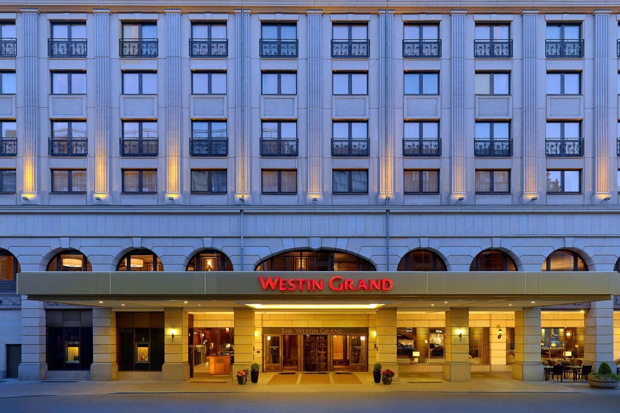 Hotel The Westin Grand Berlino Esterno foto The photo shows the exterior of a hotel, specifically the Westin Grand. The building features a classic architectural design with multiple large windows and decorative elements. The entrance is highlighted with a canopy that displays the hotel's name