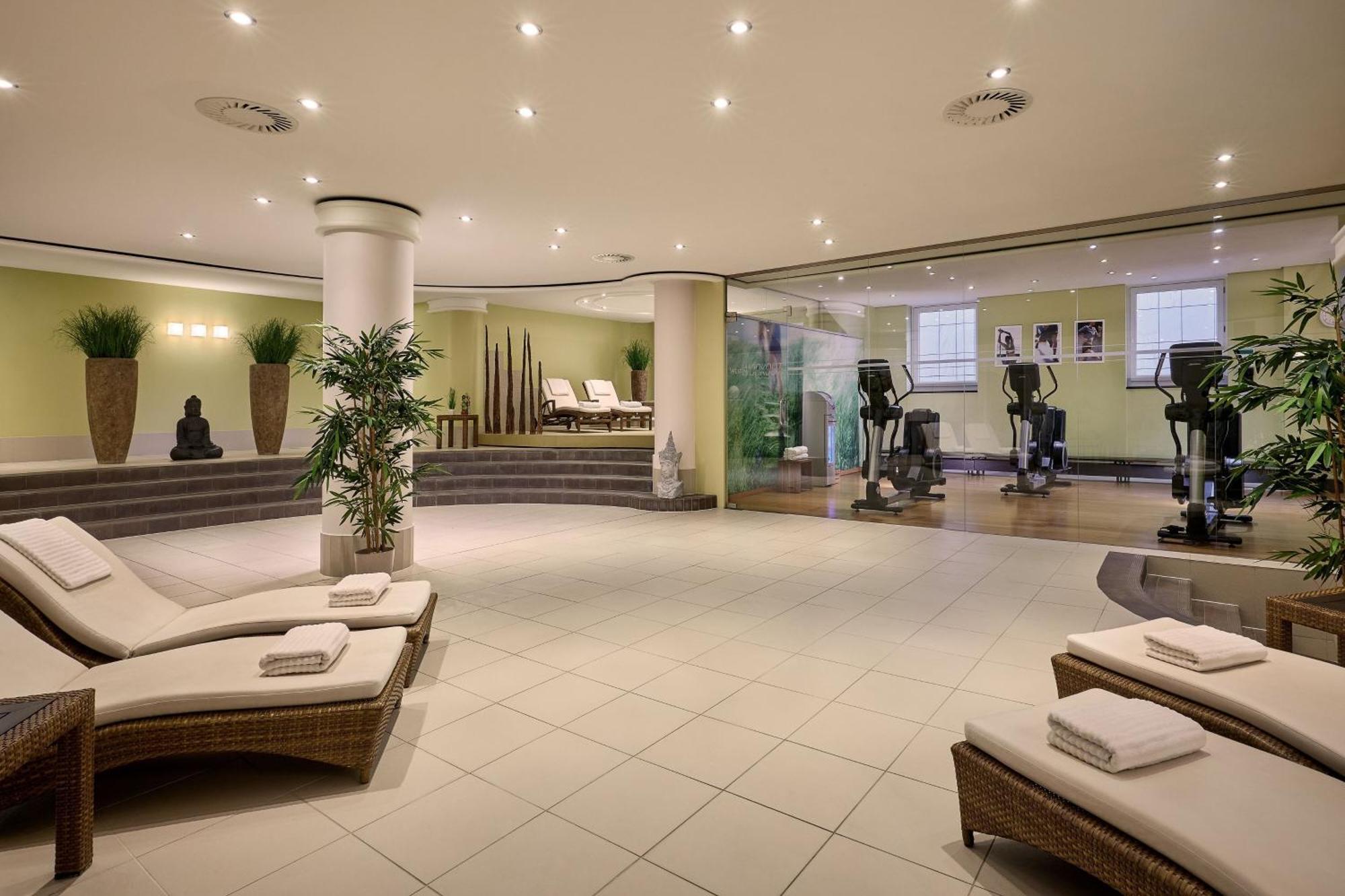 Hotel The Westin Grand Berlino Esterno foto The photo shows an interior of a wellness or spa area. It features a serene setting with comfortable lounge chairs placed on a tiled floor. The space is illuminated with bright, ambient lighting, creating a relaxing atmosphere. There are indoor plant
