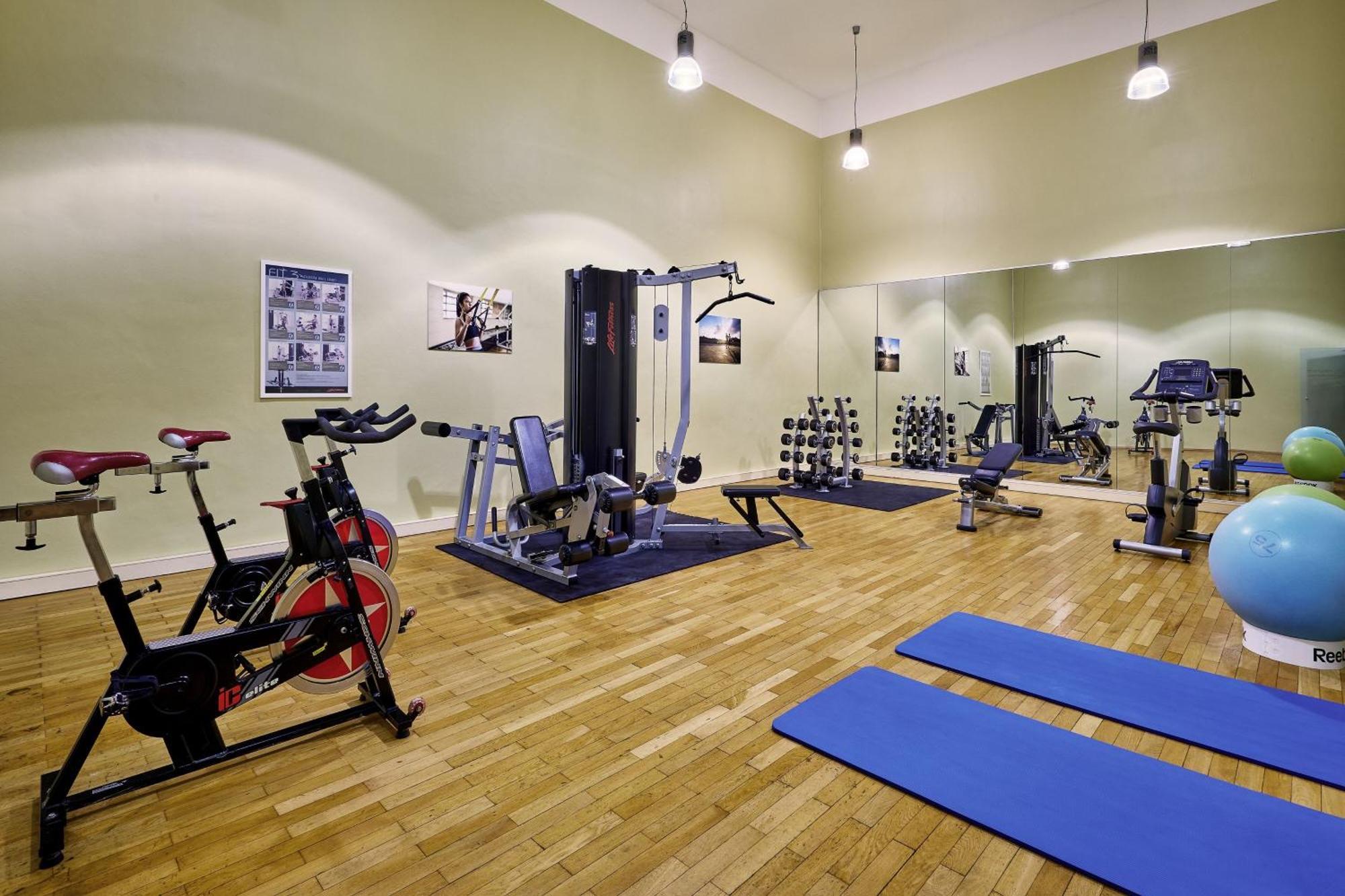Hotel The Westin Grand Berlino Esterno foto The photo depicts a fitness or workout room. It features various exercise equipment, including:

- A stationary bike on the left.
- A multi-gym machine in the center, designed for different strength training exercises.
- A set of free weights organiz